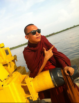 Sư Pháp Định (thế danh Phan Văn Triển) mặc áo nâu, đeo kính đen chụp hình