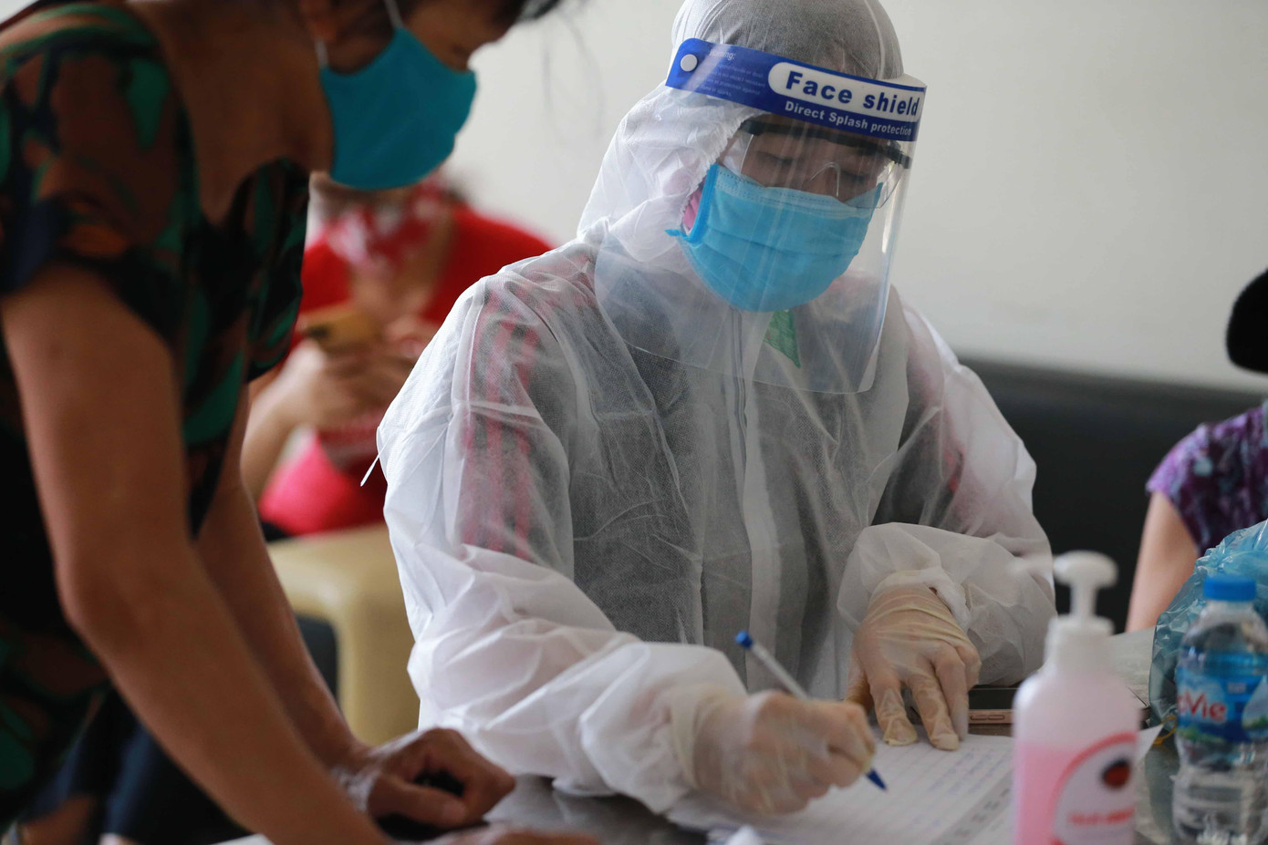 Nhân viên y tế hướng dẫn người dân khai thông tin cá nhân khi xét nghiệm 1 điểm trên địa bàn xã Tân Triều. Ảnh: NL