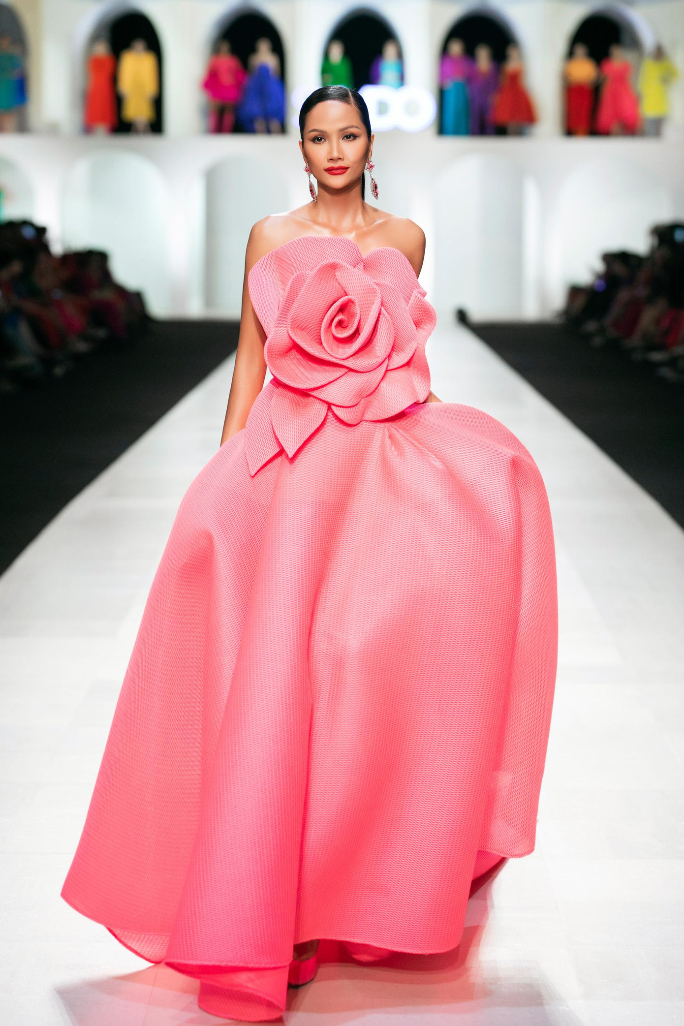 Hoa hậu H'Hen Niê đảm nhận vai trò vedette của show diễn. Cô diện váy cúp ngực màu hồng với điểm nhấn là họa tiết hoa to bản ở phần thân trên.