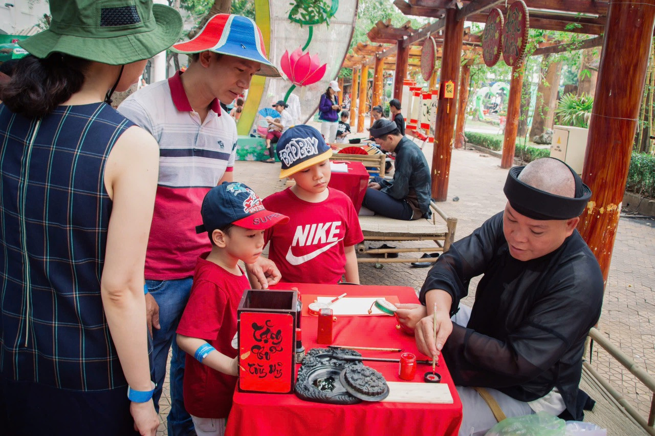 Gia đinh trẻ xin chữ ông đồ tại Công viên Văn hóa Đầm Sen dịp Tết Nguyên đán. Ảnh: Phạm Nguyễn