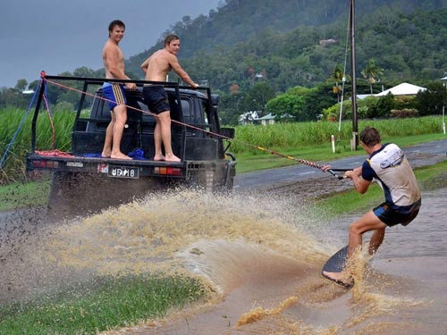 Thanh niên ở khu Cairns, bang Queensland (Úc) tận dụng nước lụt làm trò vui lướt sóng trên cạn. Ảnh: SHAY BOURNE / CATERS NEWS