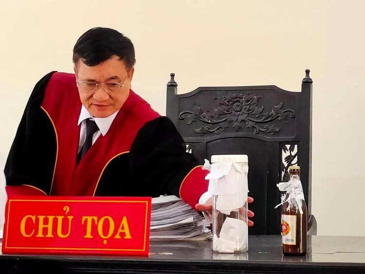 Chai bia trong vụ án được đặt trên bàn của thẩm phán chủ tọa phiên tòa sáng nay. Ảnh: Tân Châu.