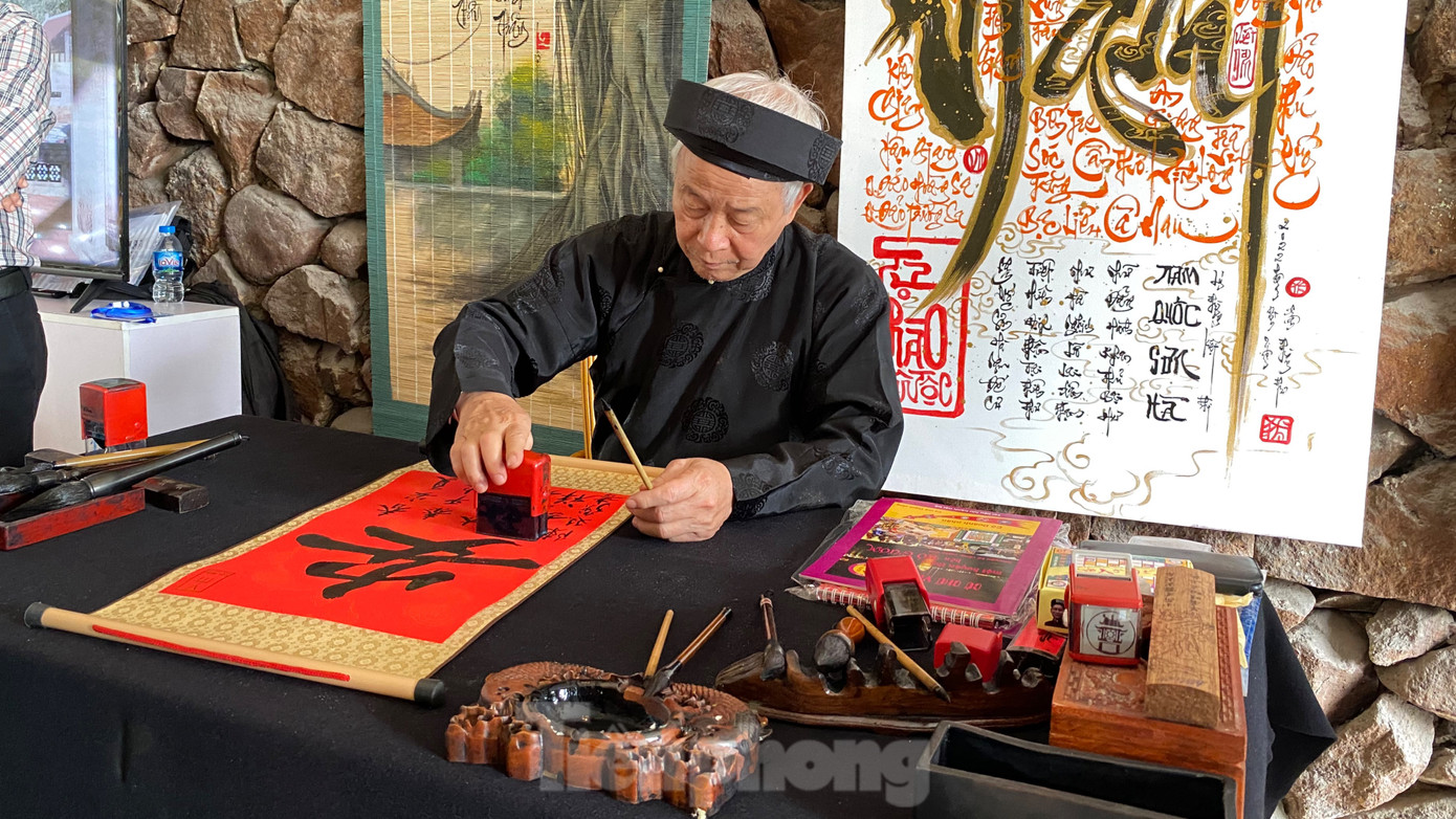 Không gian trưng bày giới thiệu về khu di tích Văn Miếu - Quốc Tử Giám, theo hai nội dung là các sản phẩm ứng dụng công nghệ 4.0 đang triển khai tại khu di tích và các sản phẩm lưu niệm đang phục vụ du khách để tham quan, trải nghiệm. Ông đồ cho chữ tại không gian trưng bày giới thiệu về khu di tích Văn Miếu - Quốc Tử Giám. Ảnh: GIA LINH.