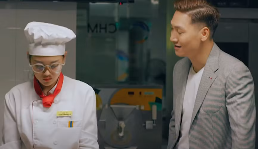 Quy (Mạnh Trường) thông báo Ly (Thùy Anh) sẽ cùng anh tham dự hội thảo về bánh. Ảnh: CMH.