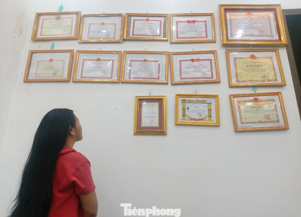 Chị Hờ T. D ngắm nhìn giấy khen, bằng khen mà Trung úy Thào A Khư nhận được sau quá trình nỗ lực triệt phá tội phạm ma túy.