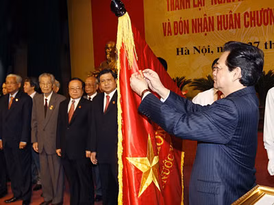 Thủ tướng Nguyễn Tấn Dũng gắn Huân chương Hồ Chí Minh lên lá cờ truyền thống của Ngân hàng Nhà nước Việt Nam Ảnh: TTXVN