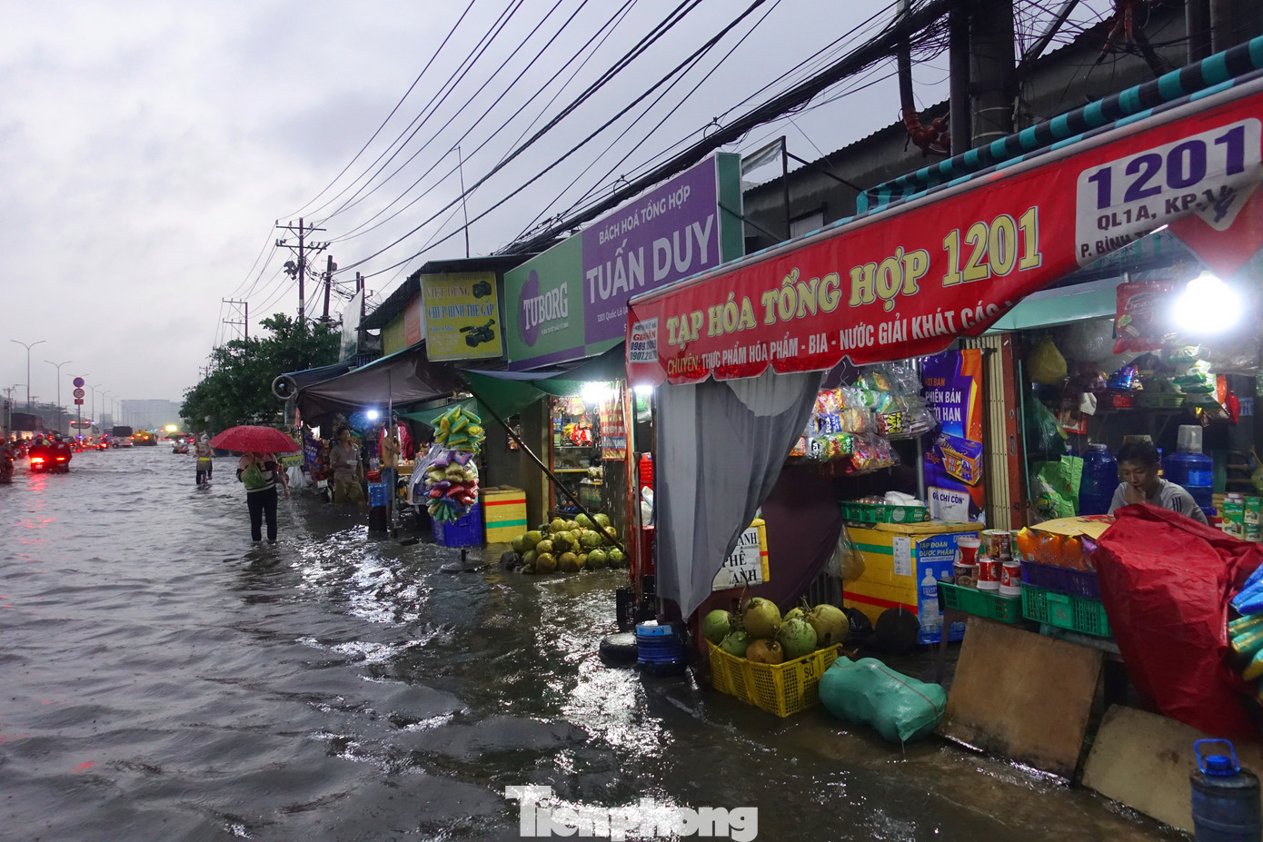 Chủ tiệm tạp hóa trên quốc lộ 1 phải dùng những tấm ván để chắn rác thải tràn vào theo dòng nước bẩn.