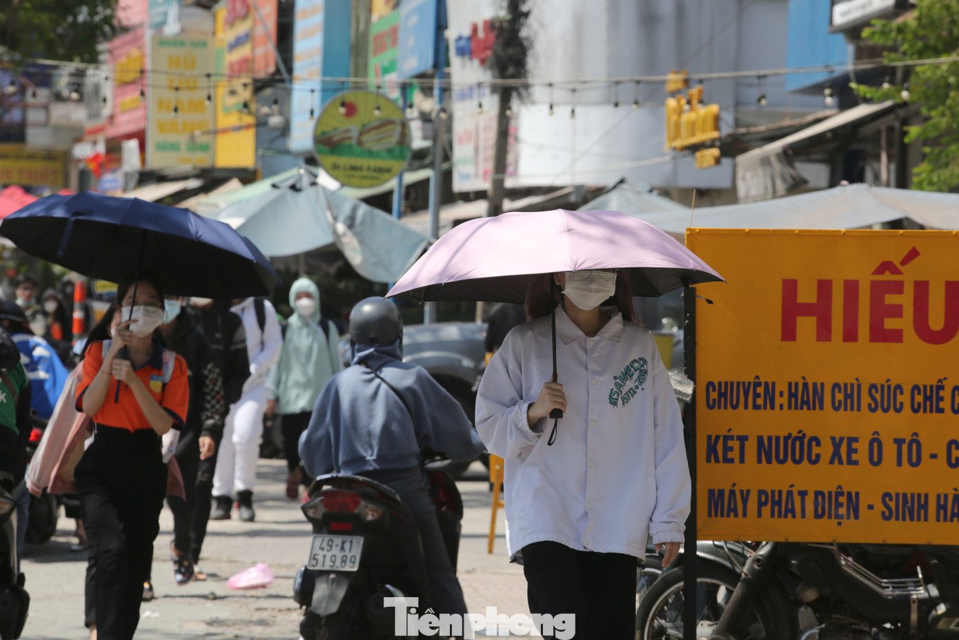 Những người ra đường vào lúc cao điểm nắng nóng dùng các biện pháp che nắng để bảo vệ sức khỏe.
