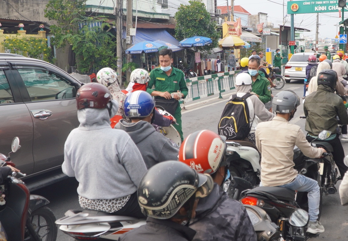 Các nhân viên bến phà bán vé từ xa cho người đi xe máy nhằm giảm ùn ứ.