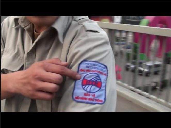 Nhân viên bảo vệ chỉ tay vào lô gô trên tay áo, cho rằng, là bảo vệ cầu nên được phép cấm phóng viên quay phim, chụp ảnh trên cầu dành cho người đi bộ. Ảnh chụp lại từ video