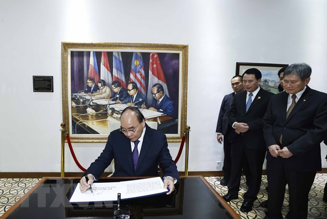 Chủ tịch nước Nguyễn Xuân Phúc viết lưu bút tại trụ sở Ban Thư ký ASEAN. (Ảnh: Thống Nhất/TTXVN)