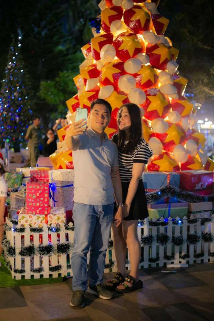 Cây thông thu hút rất nhiều cặp đôi ghé thăm, chụp ảnh kỉ niệm. "Mình biết tới cây thông này qua mạng xã hội. Khi tới nơi, cây thông đẹp, lung linh hơn mình tưởng tượng", bạn Lợi (Long Sơn - Vũng Tàu, áo xanh lá) chia sẻ (Ảnh: Quang Thành)