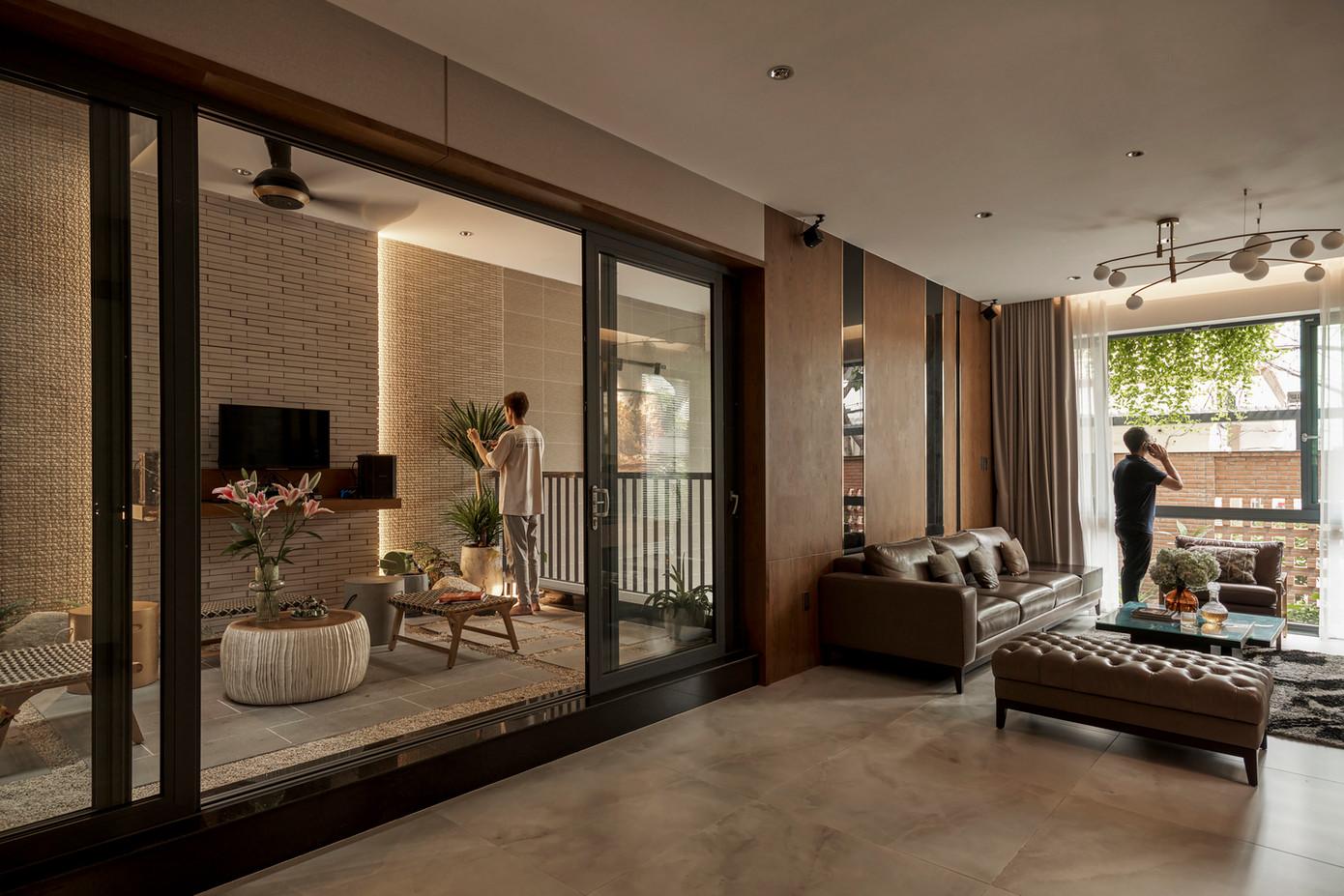 Cửa kính trượt nằm chắn giữa bên trong và bên ngoài căn nhà để tạo cảm giác thông thoáng, rộng rãi và gần gũi với thiên nhiên. Ngoài ra, chủ nhà có một khu vườn nhiệt đới và trồng rau trên sân thượng.