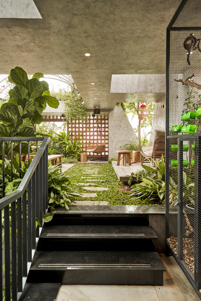 Chủ nhà yêu thích sự tối giản và mộc mạc nên màu chủ đạo của căn nhà là màu nâu và màu be. Gỗ, kính, và sàn bê tông là chất liệu chủ yếu. Để ngăn bụi, tiếng ồn hay ánh nắng trực tiếp, cây xanh được bố trí như một lá chắn dọc ban công và hành lang.