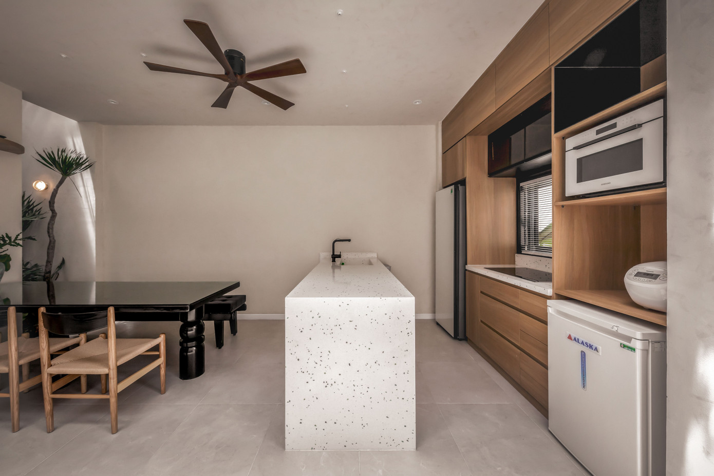 Bàn bếp được làm từ đá kim sa trắng trẻ trung, hiện đại. Một chiếc lọ nhỏ xinh đặt trên tủ đựng đồ màu trắng, đằng sau cũng là bức tường trắng, tạo nên vẻ mộc mạc, giản đơn cho không gian.