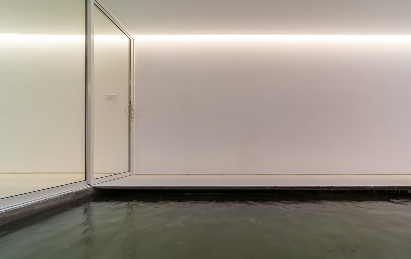 Có một ao làm mát ở mặt đất, và một cửa sổ trên mái lớn trực tiếp phía trên ao, mang đến nhiều ánh sáng cho không gian và trải nghiệm sự chuyển đổi không gian và thời gian khi một người đi bộ trong suốt một ngày.