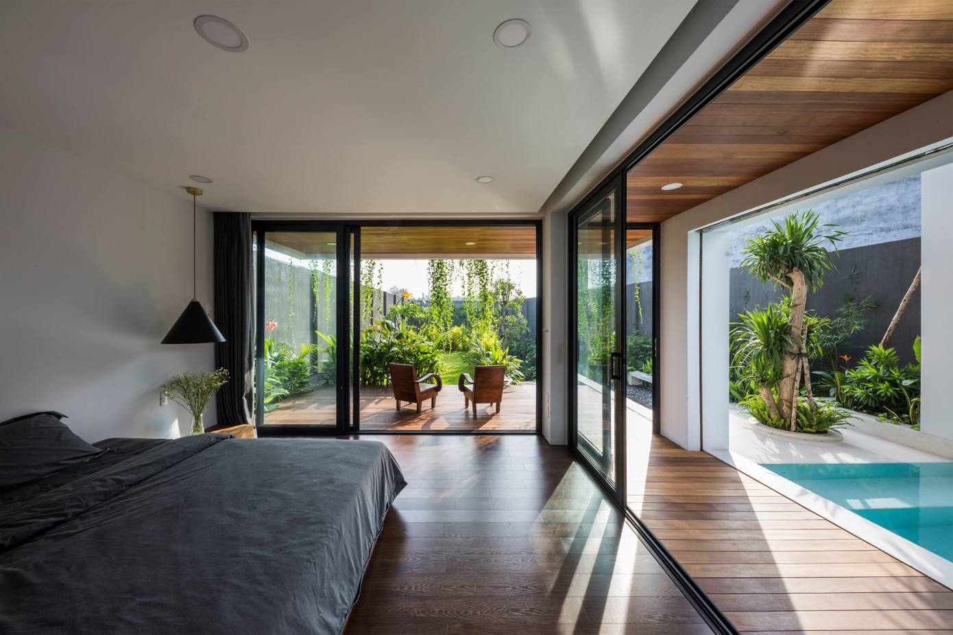 Phòng ngủ chính với lớp cửa kính lớn, nhìn ra hồ bơi và sân chính.