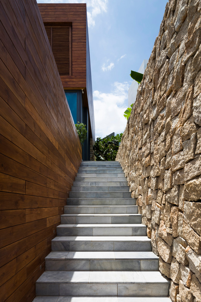 Căn nhà mở ra từ đường phía trước với một cầu thang bên ngoài dẫn đến tầng cao hơn.