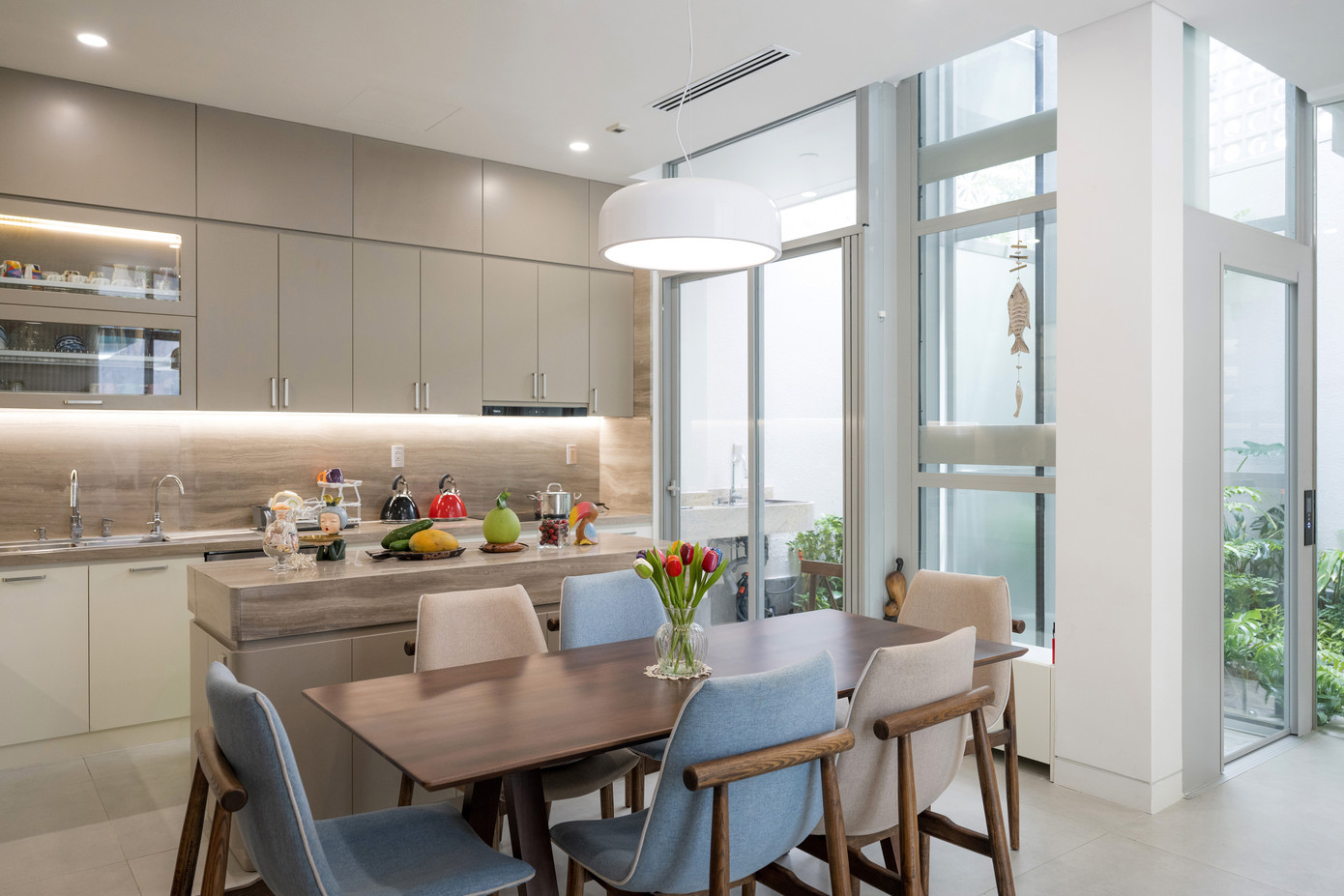 Một khoảng lùi vừa đủ từ góc hẻm được thiết kế để dành chỗ cho lối vào và khoảng sân giản dị trước nhà. Bậc tam cấp bằng đá granite được tạo hình uốn cong hướng ra sân và hệ cửa kính lớn cong lõm vào trong tạo ra một khoảng hiên nhà hình elip độc đáo ở tầng trệt. Một khoảng lùi vừa đủ từ góc hẻm được thiết kế để dành chỗ cho lối vào và khoảng sân giản dị trước nhà. Bậc tam cấp bằng đá granite được tạo hình uốn cong hướng ra sân và hệ cửa kính lớn cong lõm vào trong tạo ra một khoảng hiên nhà hình elip độc đáo ở tầng trệt.