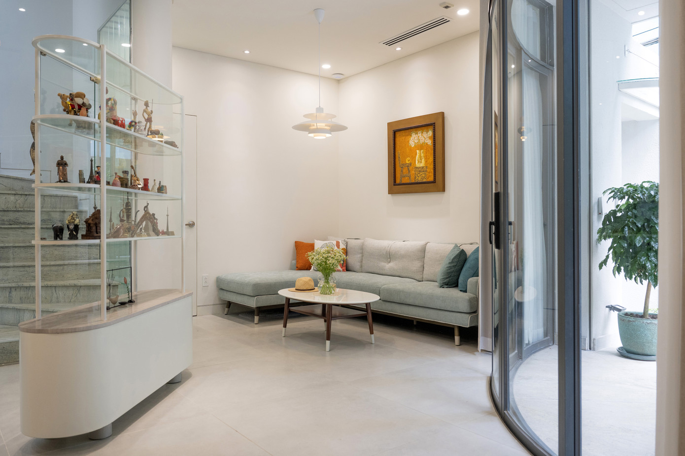 Một khoảng lùi vừa đủ từ góc hẻm được thiết kế để dành chỗ cho lối vào và khoảng sân giản dị trước nhà. Bậc tam cấp bằng đá granite được tạo hình uốn cong hướng ra sân và hệ cửa kính lớn cong lõm vào trong tạo ra một khoảng hiên nhà hình elip độc đáo ở tầng trệt. Một khoảng lùi vừa đủ từ góc hẻm được thiết kế để dành chỗ cho lối vào và khoảng sân giản dị trước nhà. Bậc tam cấp bằng đá granite được tạo hình uốn cong hướng ra sân và hệ cửa kính lớn cong lõm vào trong tạo ra một khoảng hiên nhà hình elip độc đáo ở tầng trệt.