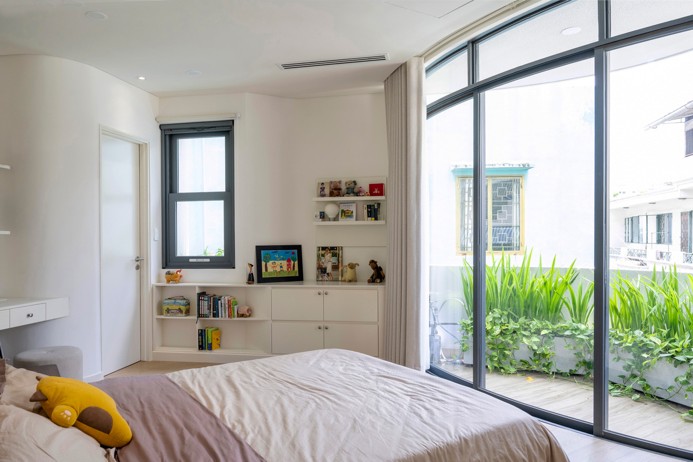 Góc nhà uốn cong ở tầng 2 được dành cho phòng ngủ chính của gia chủ với một hệ cửa sổ kính lớn tích hợp bồn cây được uốn cong. Góc nhà uốn cong ở tầng 2 được dành cho phòng ngủ chính của gia chủ với một hệ cửa sổ kính lớn tích hợp bồn cây được uốn cong.