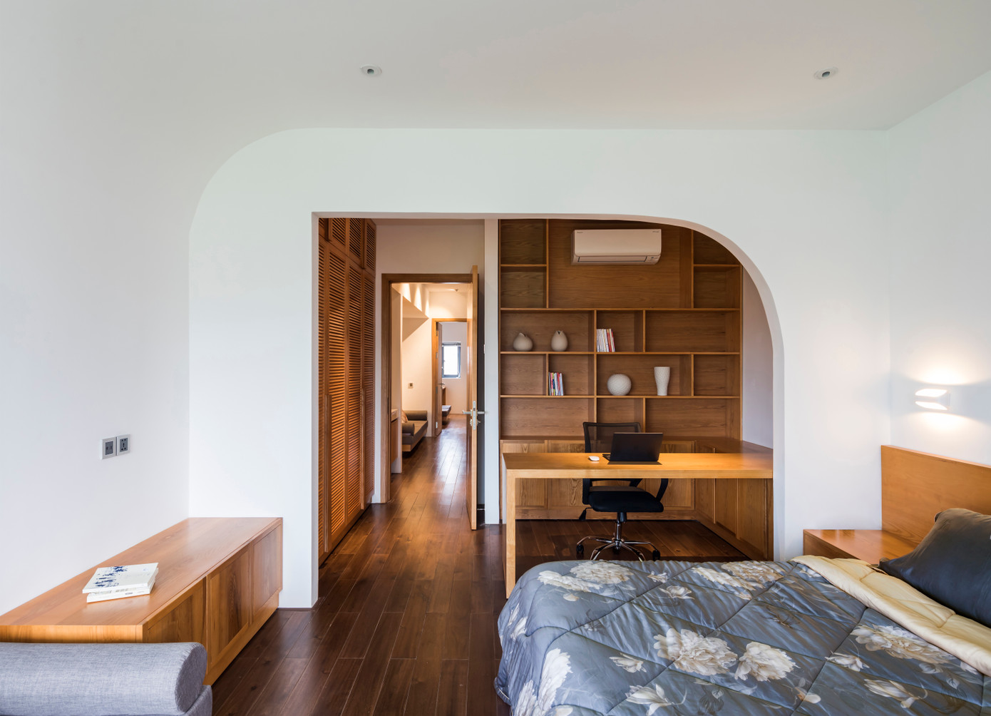 Đường cong lệch của bức tường tạo sự ngăn cách giữa giường ngủ và bàn làm việc.