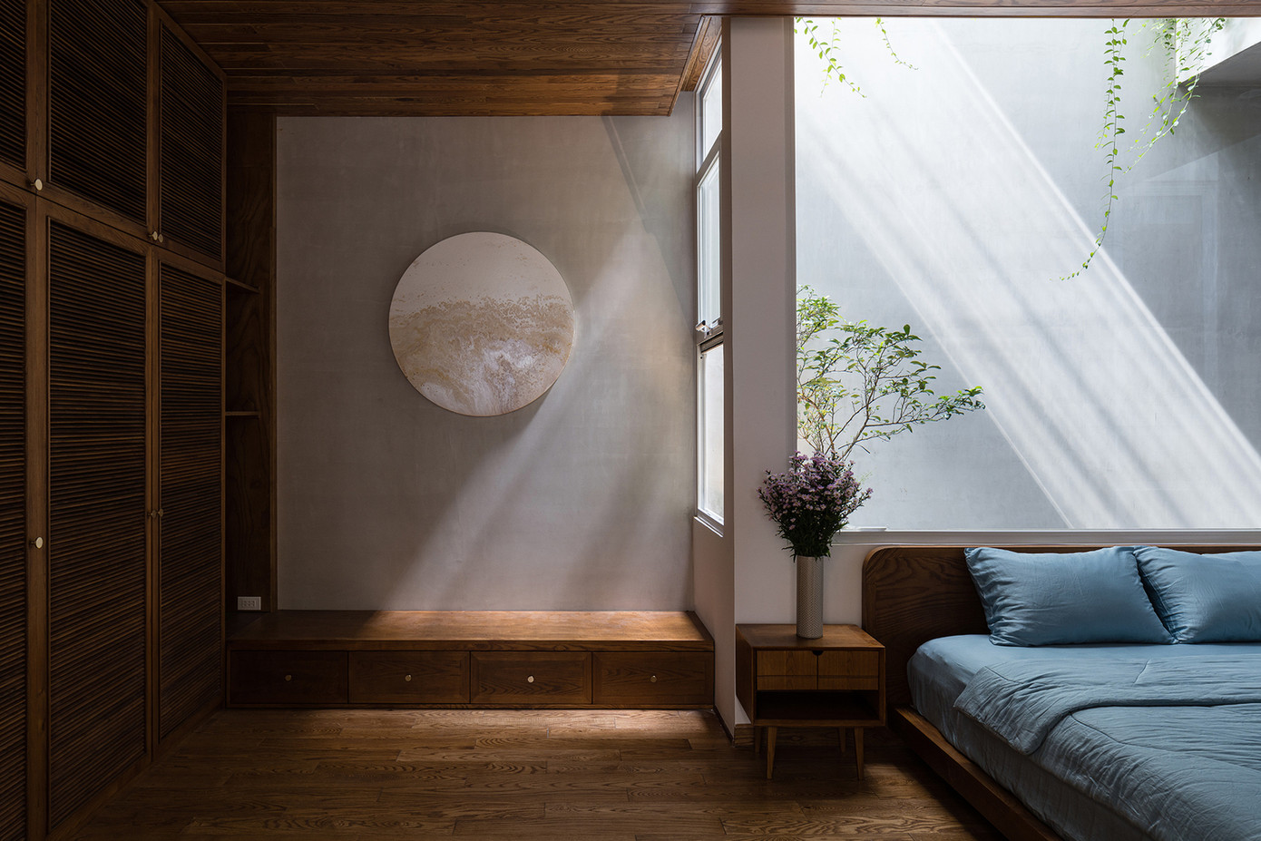 Bức vẽ hình tròn và lọ hoa tím tô điểm cho căn phòng ngủ thêm ấm cúng.