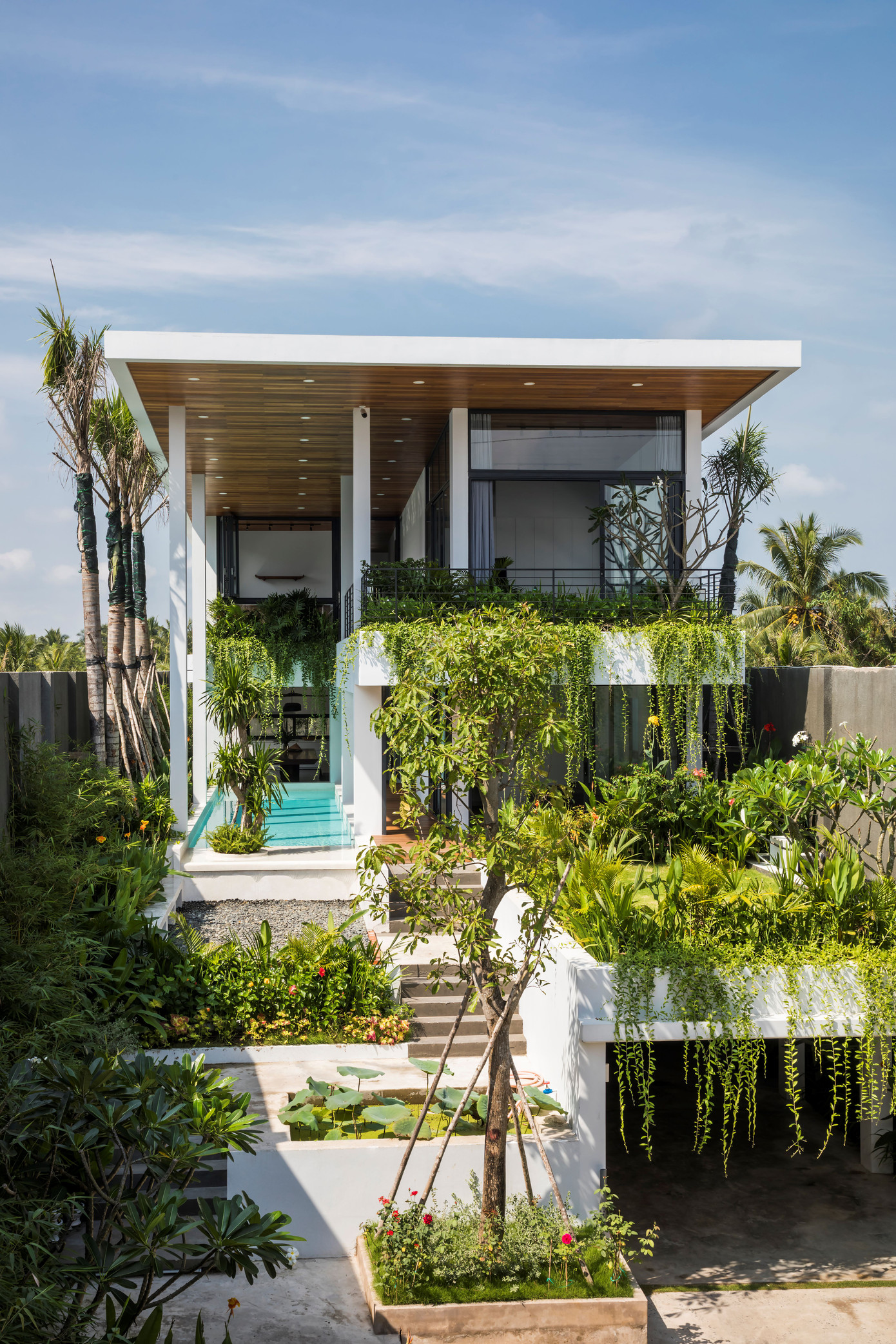 Mặt bằng tầng trệt được nâng cao lên như một quả đồi nhỏ, xung quanh phủ cây xanh.