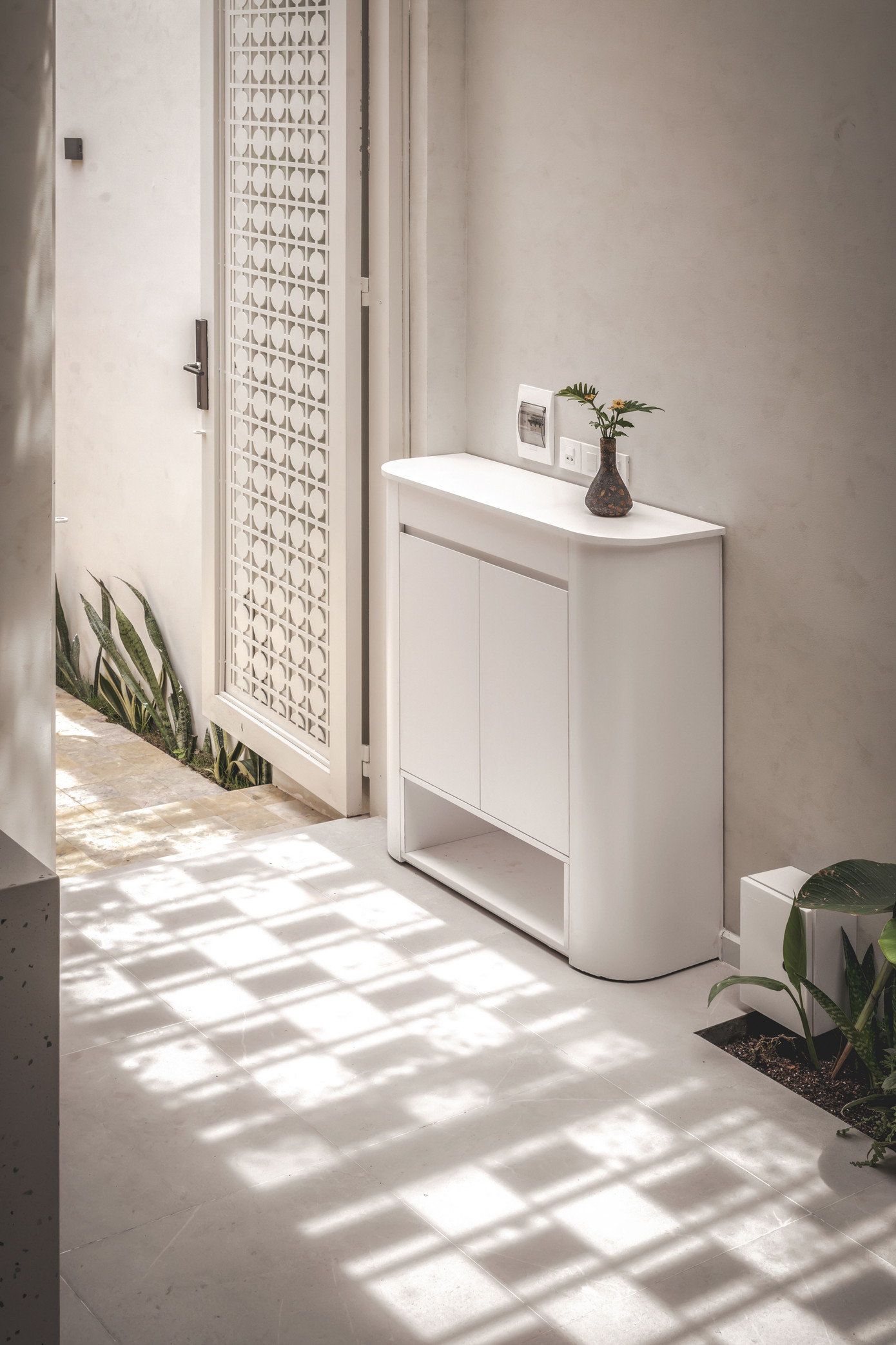 Một chiếc lọ nhỏ xinh đặt trên tủ đựng đồ màu trắng, đằng sau cũng là bức tường trắng, tạo nên vẻ mộc mạc, giản đơn cho không gian.