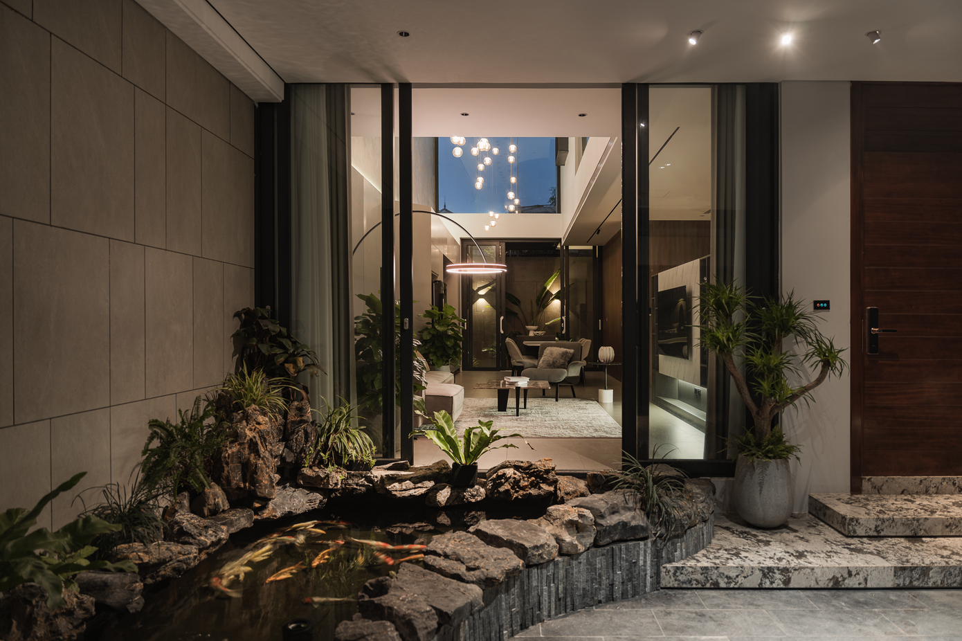 Tấm cửa kính lớn giúp người bên trong phòng khách có thể nhìn trực tiếp ra bể cá và cảnh quan bên ngoài.