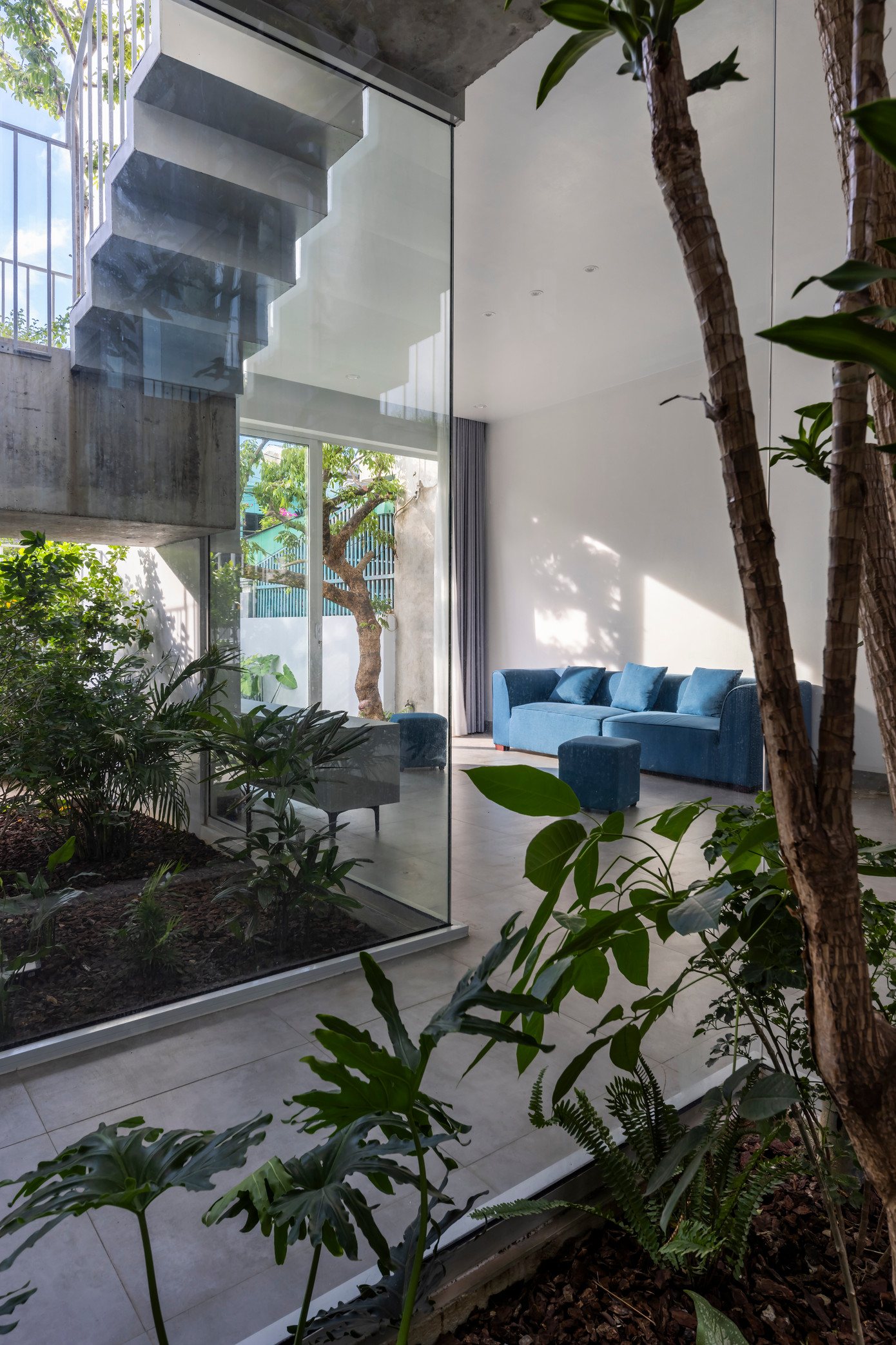 Màu xanh của ghế sofa phòng khách đồng điệu với sắc xanh của cỏ cây trong vườn.