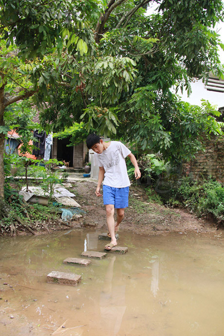 Để vào nhà em Đích, phải đi qua một vũng nước khá to. Nếu trời mưa lớn, vũng nước này ngập tới trên đầu gối. Những lúc đó, hai mẹ con chỉ bó gối ngồi nhà. Ảnh: Trường Phong