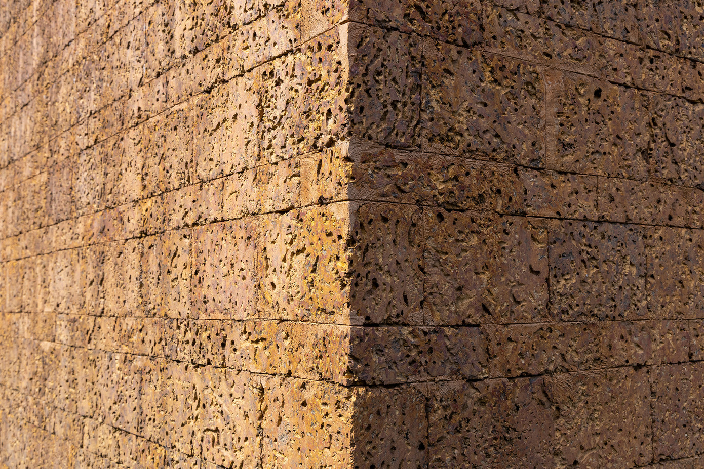 Phần tường sử dụng đá ong địa phương để cách nhiệt, cách âm, tạo sự gần gũi cũng như đồng điệu với phần gỗ trần mái.