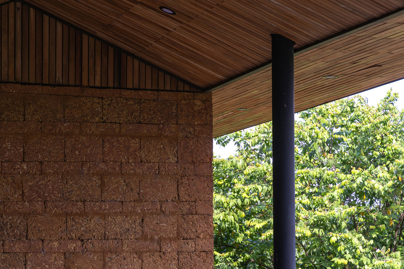 Phần tường sử dụng đá ong địa phương để cách nhiệt, cách âm, tạo sự gần gũi cũng như đồng điệu với phần gỗ trần mái.