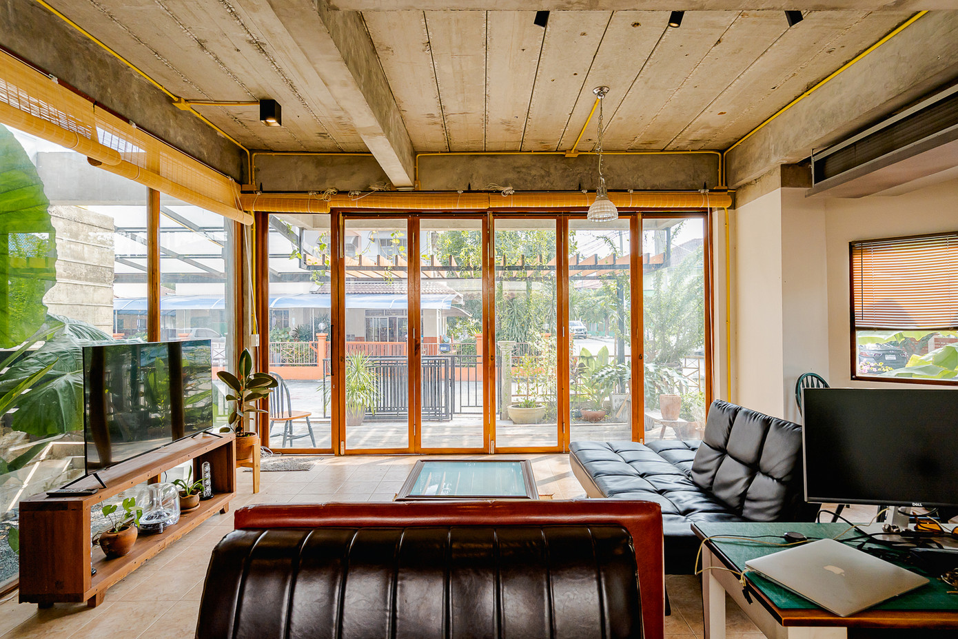 Không gian phòng khách rộng mở, tràn ngập ánh sáng và khí trời. Xen kẽ giữa các mảng tường là màu xanh của cây cối.