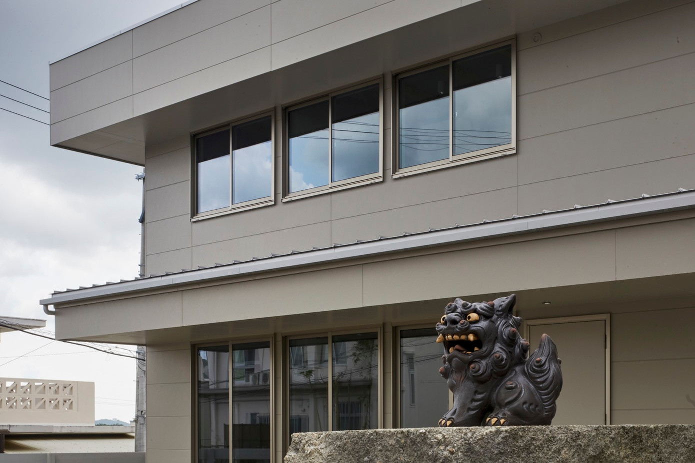 Ngôi nhà này là tổ ấm của một gia đình gồm 3 thành viên với bối cảnh xung quanh là những ngôi nhà mang đặc trưng của vùng Okinawa (Nhật Bản) với phần mái gần như bằng phẳng và có phần hiên lớn đua ra giúp giảm bớt tác động gay gắt của ánh nắng mặt trời.