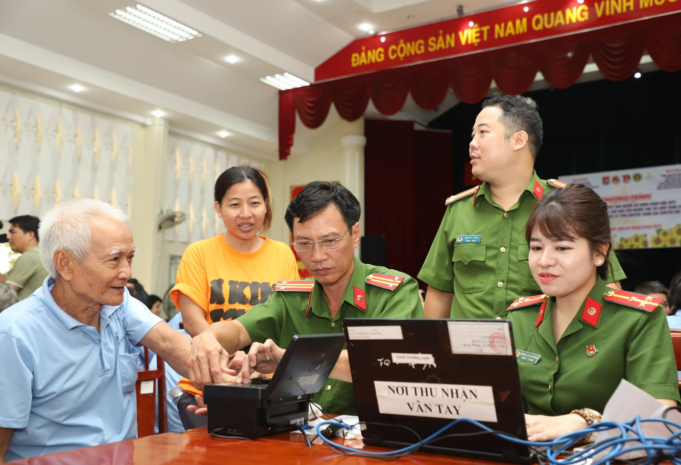 Cán bộ CATP hỗ trợ người khuyết tật thực hiện các bước làm thẻ căn cước. Ảnh: Ngô Tùng