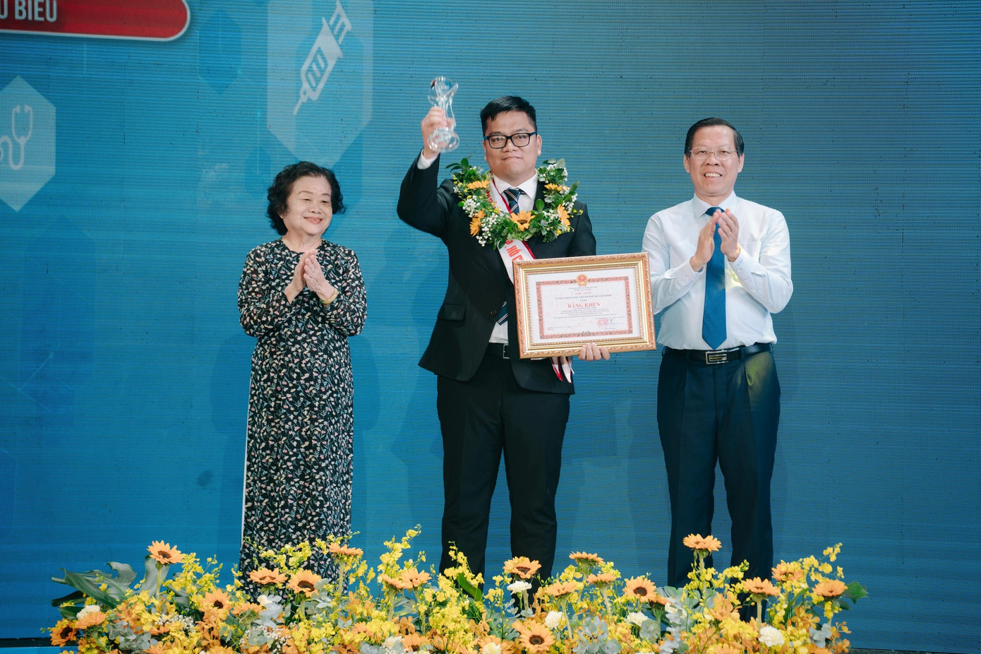 Ông Phan Văn Mãi - Chủ tịch UBND TPHCM và nguyên Phó Chủ tịch nước - bà Trương Mỹ Hoa trao bằng khen cho anh Nguyễn Phước Vinh - Trưởng phòng Khoa học công nghệ và Hợp tác quốc tế, Phó Trưởng khoa Dược, Trường Đại học Khoa học sức khỏe, Đại học Quốc gia TPHCM.
