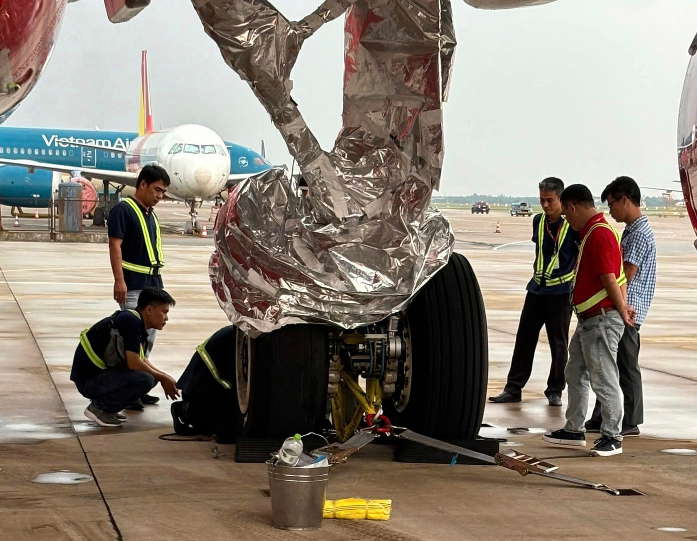 Các kỹ sư chằng dây giữa càng máy bay. Ảnh NIA. Các kỹ sư chằng dây giữa càng máy bay. Ảnh NIA.