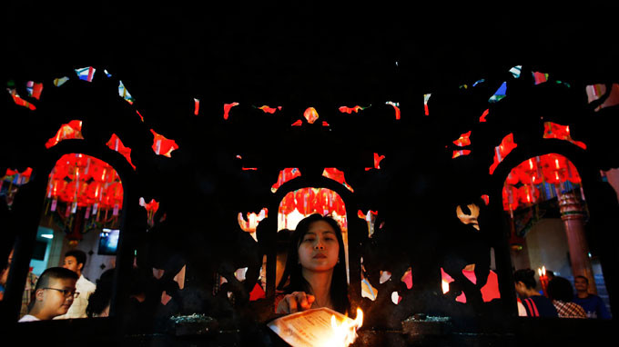 Một người Thái đốt giấy tiền vàng bạc tại thủ đô Bangkok. Ảnh: Reuters 