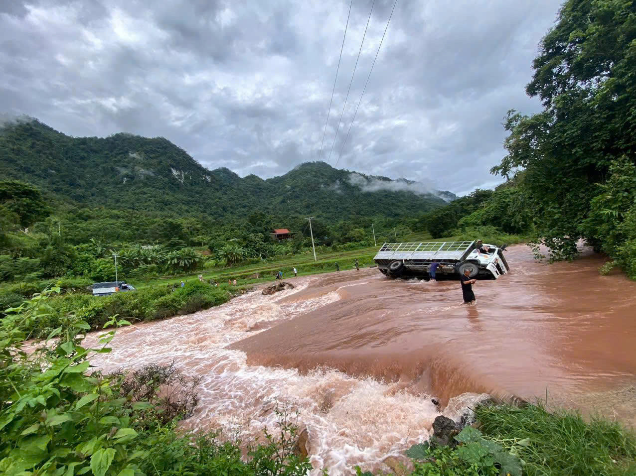 Xe tải bị lật nghiêng khi cố băng qua đoạn đường ngập nước. Ảnh: CTV Xe tải bị lật nghiêng khi cố băng qua đoạn đường ngập nước. Ảnh: CTV