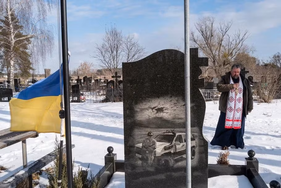 Linh mục Kostyantyn Kholodov, một tuyên úy quân đội, cầu nguyện ngày 6/22 ở Bucha, Ukraine, bên ngôi mộ của hai người đàn ông địa phương thiệt mạng trong cuộc xung đột với lực lượng ly khai ở miền đông nước này. Ảnh: The Washington Post. Linh mục Kostyantyn Kholodov, một tuyên úy quân đội, cầu nguyện ngày 6/22 ở Bucha, Ukraine, bên ngôi mộ của hai người đàn ông địa phương thiệt mạng trong cuộc xung đột với lực lượng ly khai ở miền đông nước này. Ảnh: The Washington Post.