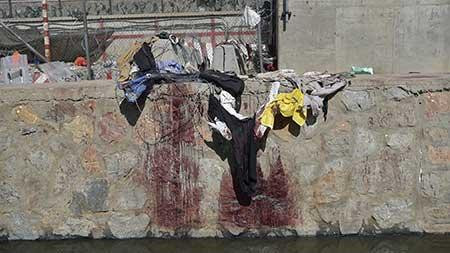 Quần áo và vết máu trên bờ kè kênh dẫn nước thải sau vụ nổ. Ảnh: Getty Images.