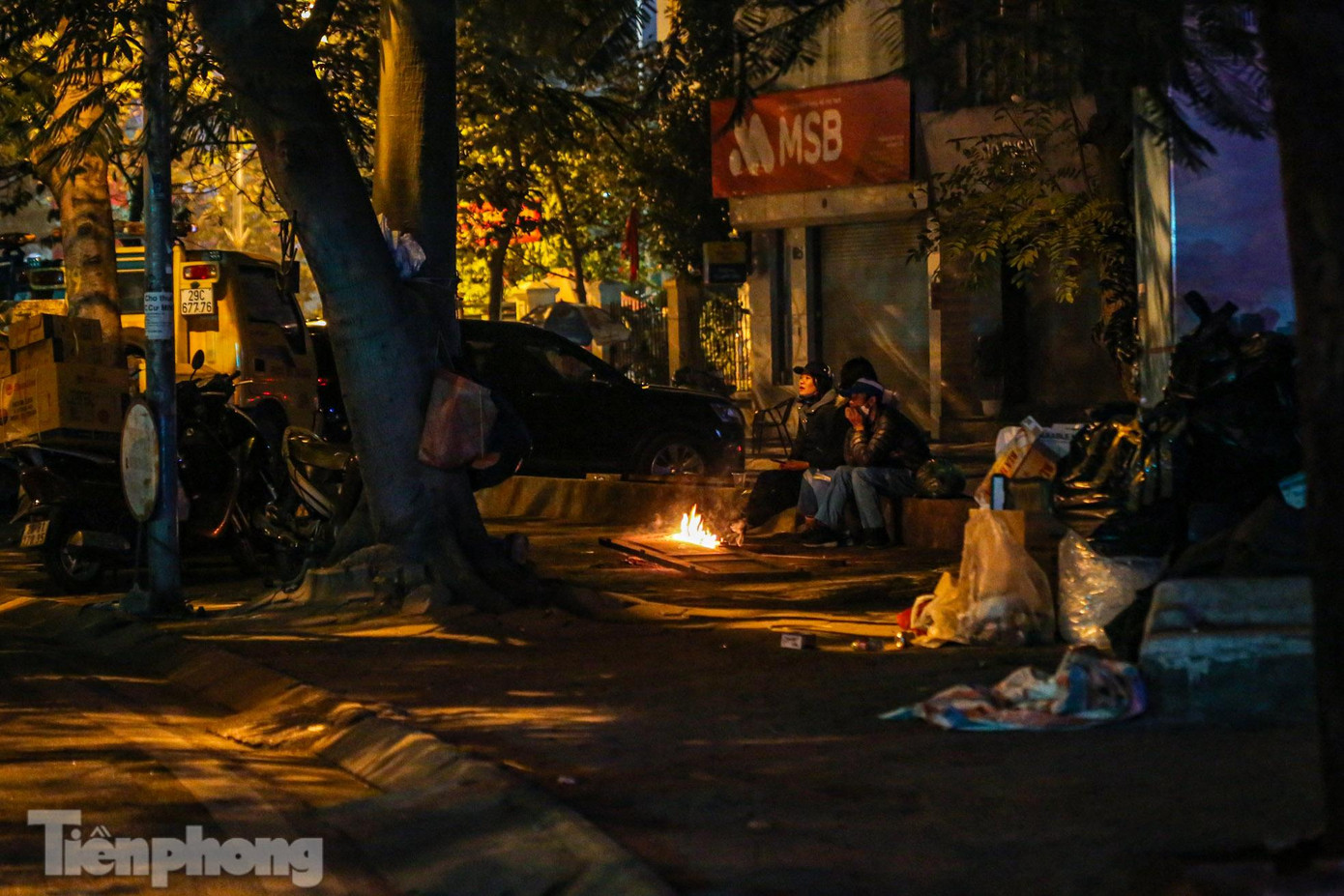 Nhân viên vệ sinh môi trường đốt lửa sưởi ấm tại vỉa hè phố Hoàng Cầu.