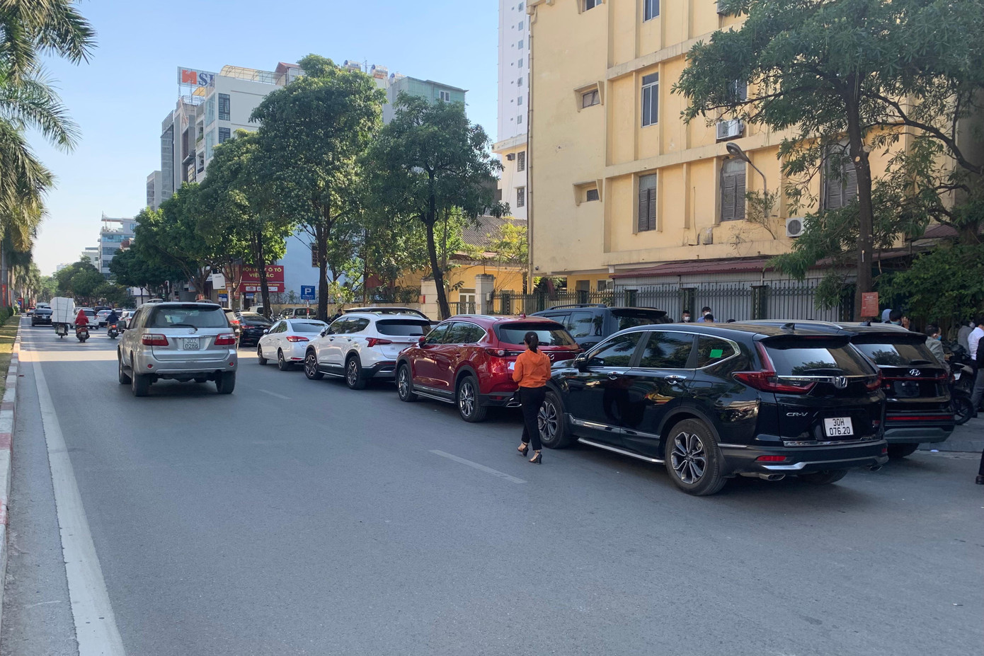 Bên ngoài điểm đăng ký, hai hàng xe ô tô xếp nối đuôi nhau dài dưới lòng đường Nguyễn Khuyến.