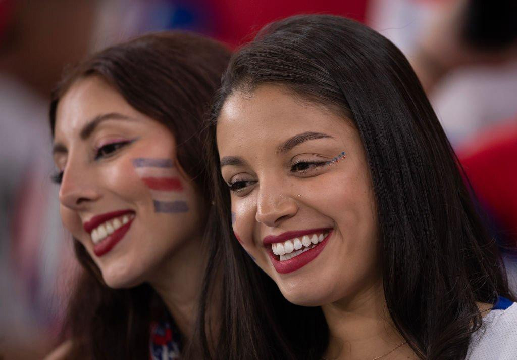 2 fan nữ tươi cười rạng rỡ trên khán đài sân Al Thumama trước trận đấu.