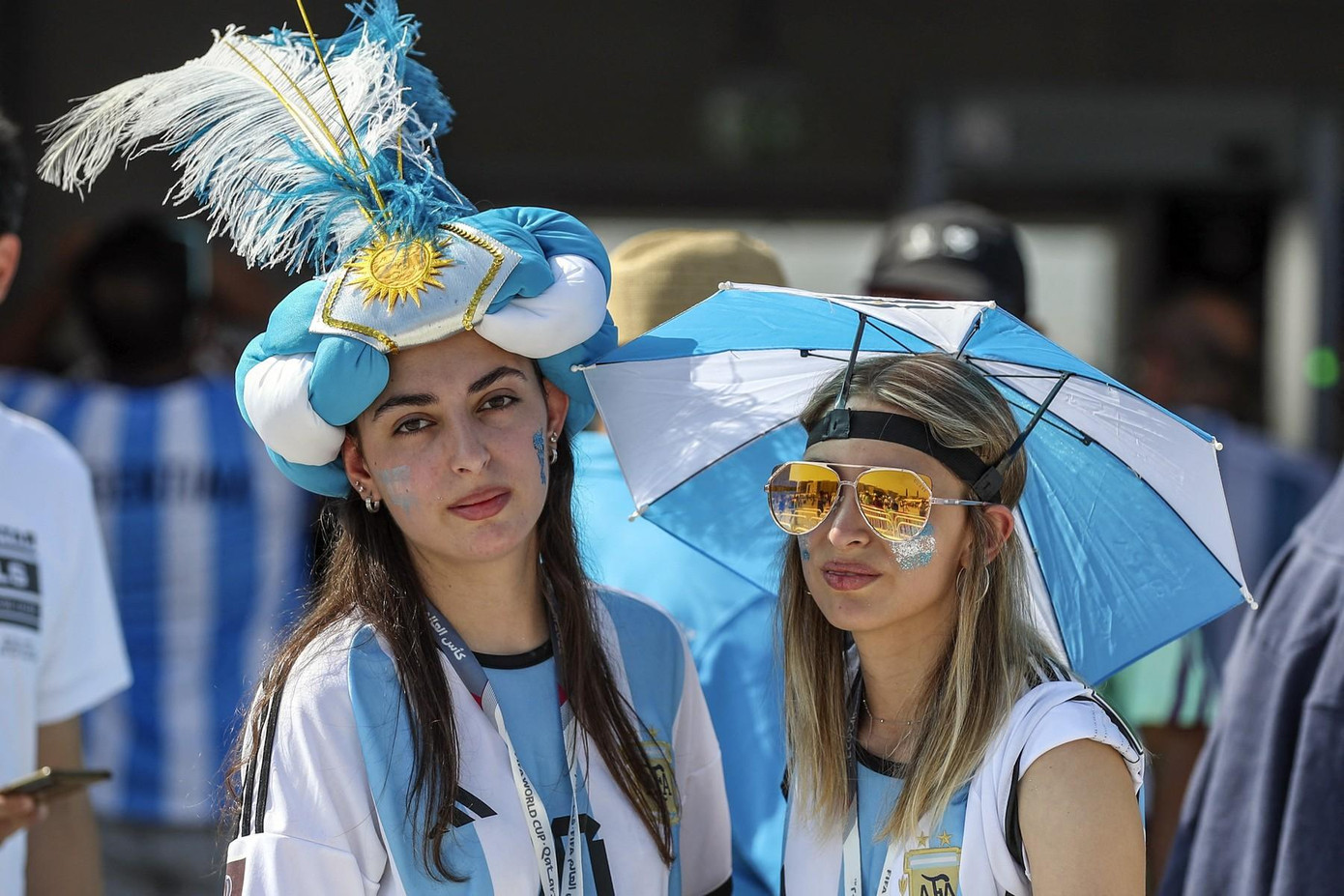 2 fan nữ mang theo mũ và ô với sắc màu Quốc kỳ Argentina.