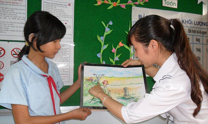 Em Hà được cô giáo hướng dẫn trong buổi học vẽ tranh.