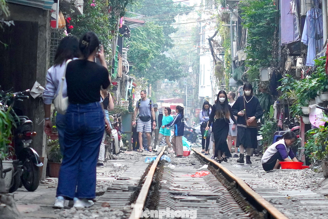 Một đoàn du khách châu Á được hướng dẫn viên du lịch hướng dẫn du khách đi bộ trên đường ray tàu hỏa.