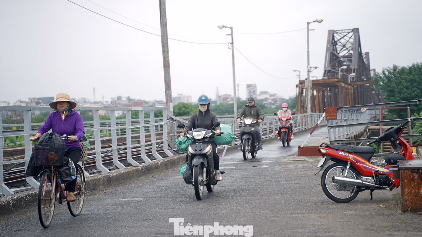 Người dân đi lại trên cầu Long Biên trong mưa nhỏ và gió thổi mạnh.